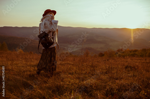 Autumn outdoor photo of fashionable woman posing on mountain during the sunset. Copy, empty space for text