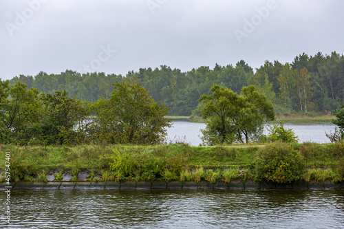 Scenic river landscape with green trees in early autumn