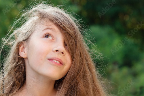 Beautiful teenager girl  with happy facial expression looking up. Close up. Front view. Happy kid outdoors
