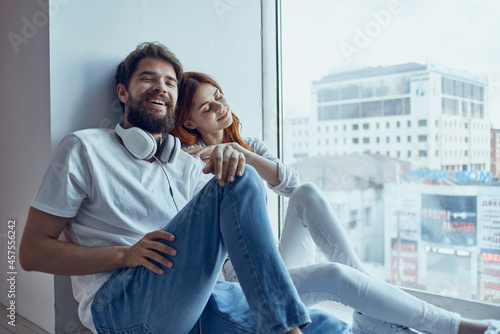 a young couple sit near the window with headphones together apartments