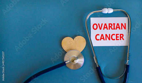Ovarian cancer symbol. White card with words Ovarian cancer, beautiful blue background, wooden heart and stethoscope. Medical and ovarian cancer concept.