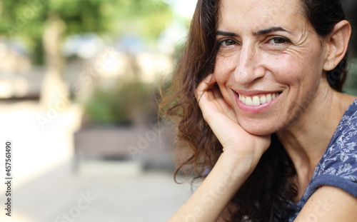 Portrait of beautiful natural 50 years old woman sitting in street cafe