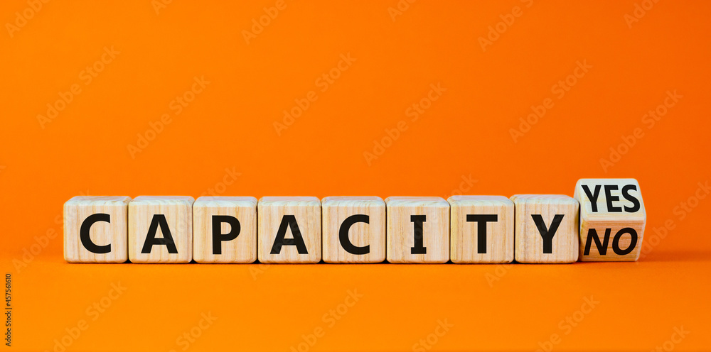 Capacity symbol. Turned a wooden cube and changed words 'capacity no' to 'capacity yes'. Beautiful orange background. Business and capacity concept, copy space. Capacity symbol. Turned a wooden cube and changed words 'capacity no' to 'capacity yes'. Beautiful orange background. Business and capacity concept, copy space.