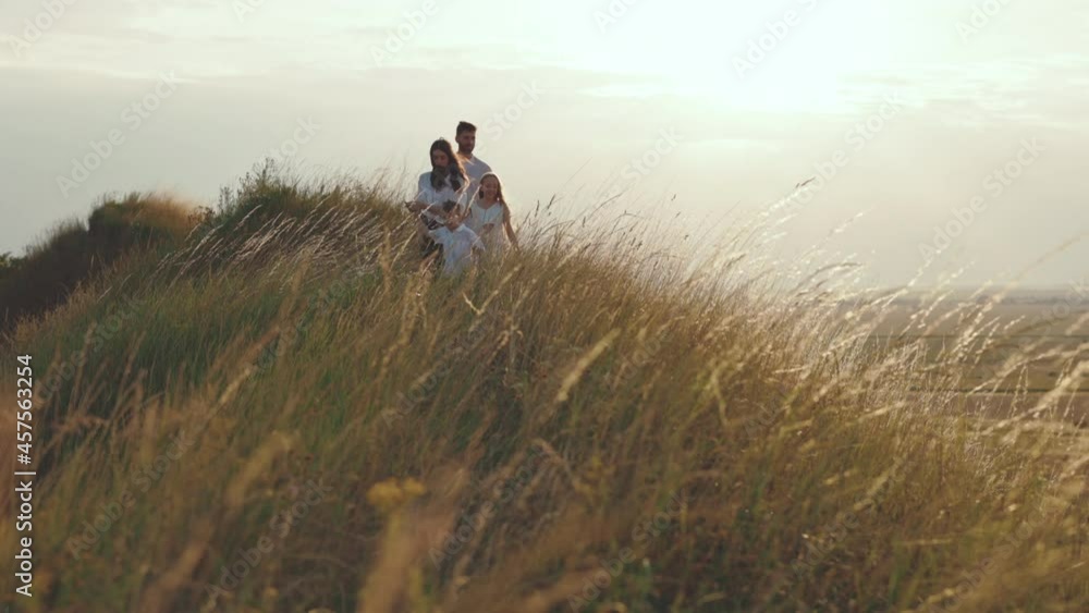 Two kids with parents walking on hill during sunny weather Two kids with parents walking on hill during sunny weather