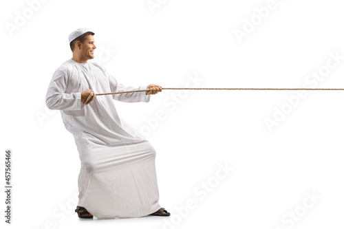 Full length profile shot of a man in ethnic clothes pulling a rope