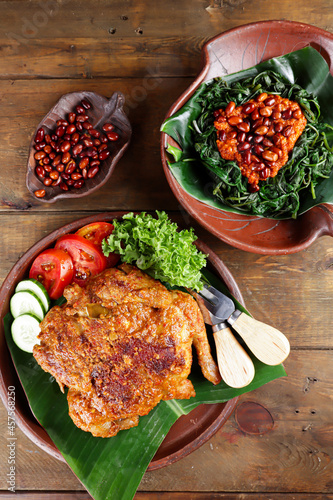 Ayam bakar Taliwang  is a traditional roast chicken from Lombok Indonesia on a wooden background, served with plecing. photo