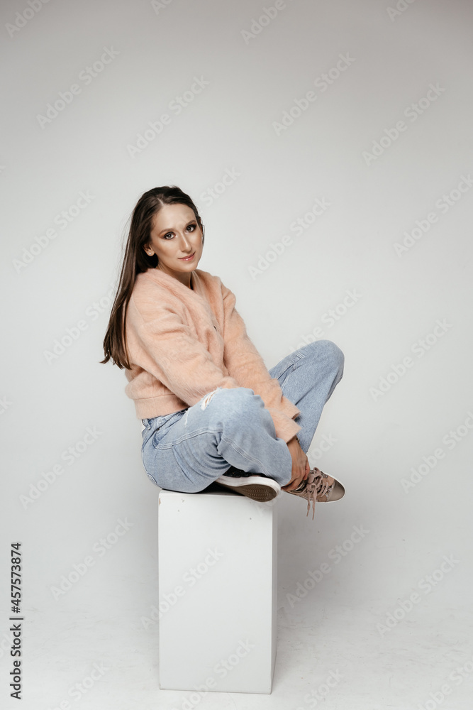 Young hipster woman wearing pink sweatshirt, hat, jeans and sneakers. Fashion studio shot Young hipster woman wearing pink sweatshirt, hat, jeans and sneakers. Fashion studio shot