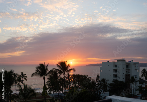 Beautiful orange sunset with dark foreground palm trees overlooking the water on the coast of Mexico