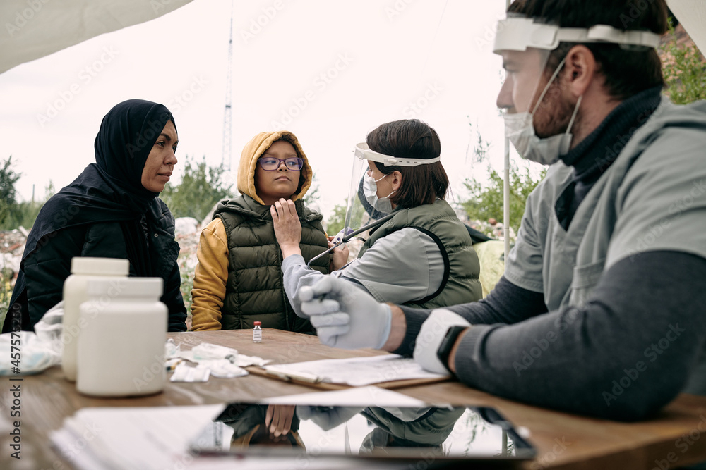 Φωτογραφία Medical specialist examining health of girland talking to her muslim mother outd