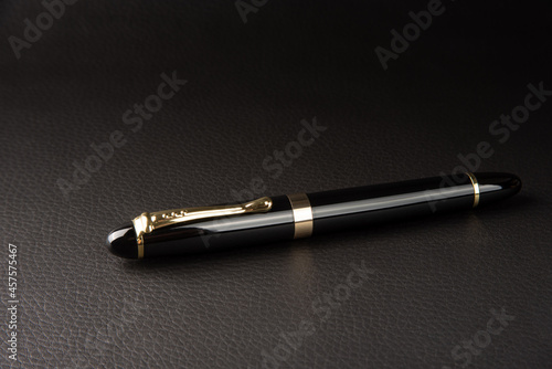Fountain pen, beautiful details of a beautiful fountain pen, placed on black leather, selective focus.