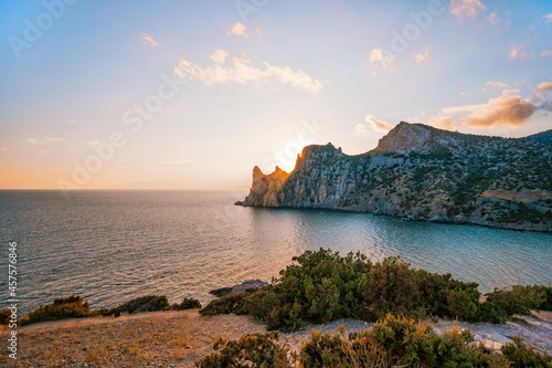 A delightful landscape at sunset from Cape Kapchik in the Crimea. Mountain view and the sea at an orange sunset.