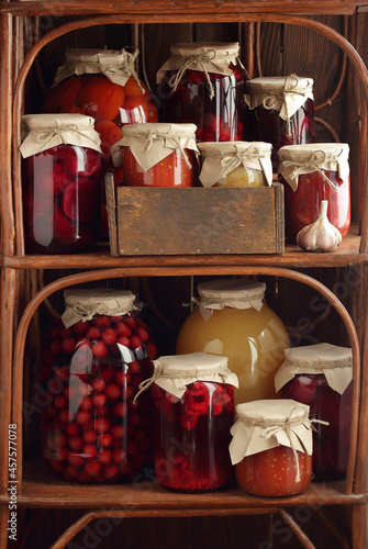 Fototapeta Naklejka Na Ścianę i Meble -  Assortment of canned preserves: fruit jam, compote, tomato paste and vegetable cans in the pantry on rustic wooden shelves, closeup, canned produce, saving leftovers, home storage organization concept