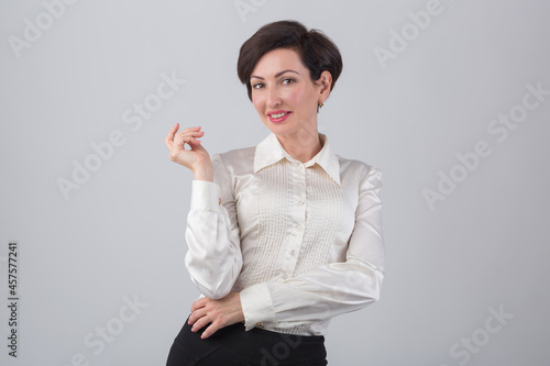 Beautiful business woman with coquettish toothy smile wearing classic formal shirt. Studio portrait of model in 40s posing with playful facial expression. Female with bob haircut and red lipstick