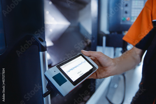 Fotografie Industrial worker measures roughness and frequency of machined part after lathe