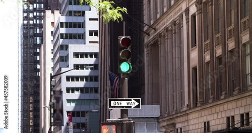 Road crossing traffic lights of New York changing from green, amber, red on the high buildings background. One way sign hanging at the pillar. Urban motives concept