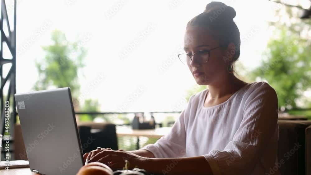 Young mixed race woman working with laptop in cafe at tropical location. Asian caucasian female studying using internet. Business woman doing social marketing work and shopping. Telecommuting concept. Young mixed race woman working with laptop in cafe at tropical location. Asian caucasian female studying using internet. Business woman doing social marketing work and shopping. Telecommuting concept.