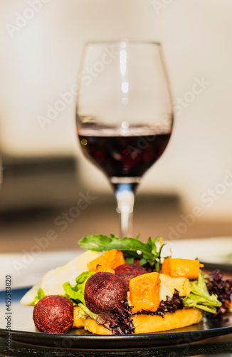 beetroot falafel salad and a glass of red wine on a table