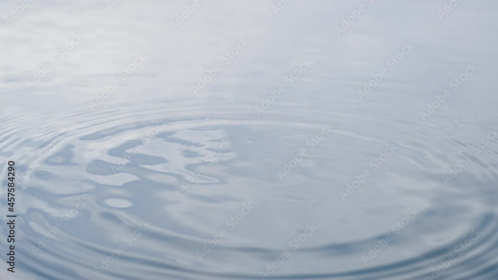 A wonderful abstract drop of water falls on a liquid surface with light waves and creates a big beautiful splash of water, from the center of the wave circles are moving. Close-up in slow motion. A wonderful abstract drop of water falls on a liquid surface with light waves and creates a big beautiful splash of water, from the center of the wave circles are moving. Close-up in slow motion.