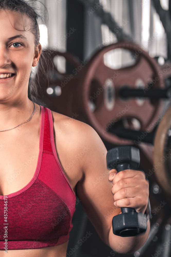 Young woman with dumbbells in the gym. Portrait of young attractive woman in sport clothes holding weight dumbbell doing fitness workout Young woman with dumbbells in the gym. Portrait of young attractive woman in sport clothes holding weight dumbbell doing fitness workout