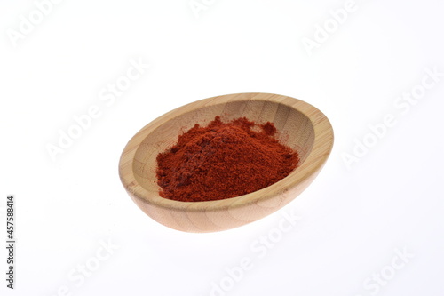 Red ground paprika on a wooden bowl against a white background. Spices. Food.