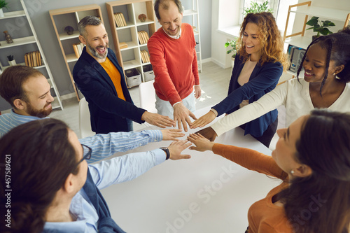 Collaborate community relationship, motivation meeting concept. Happy diverse multi-ethnic people group join helping hands in circle together gesturing common spirit, unity and teamwork in office photo