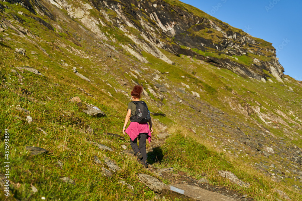 Woman hiker with backpack on a trail in the mountains