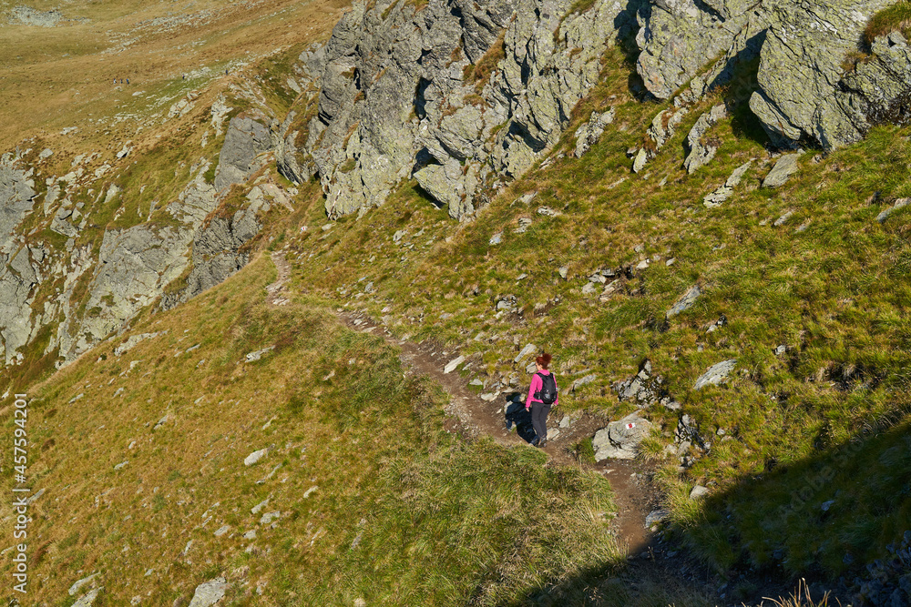 Woman hiker with backpack on a trail in the mountains Woman hiker with backpack on a trail in the mountains