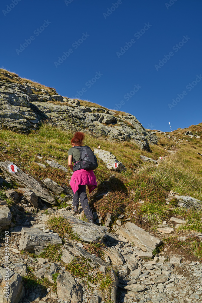 Woman hiker with backpack on a trail in the mountains