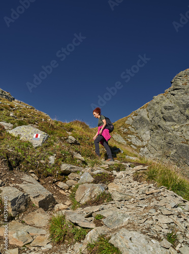 Woman hiker with backpack on a trail in the mountains