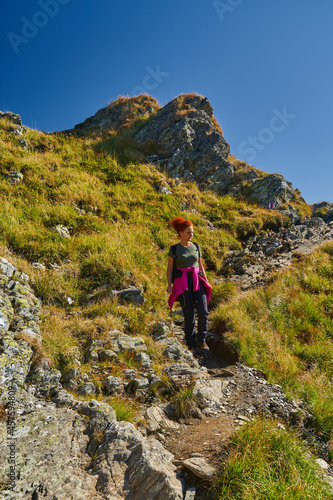 Woman hiker with backpack on a trail in the mountains