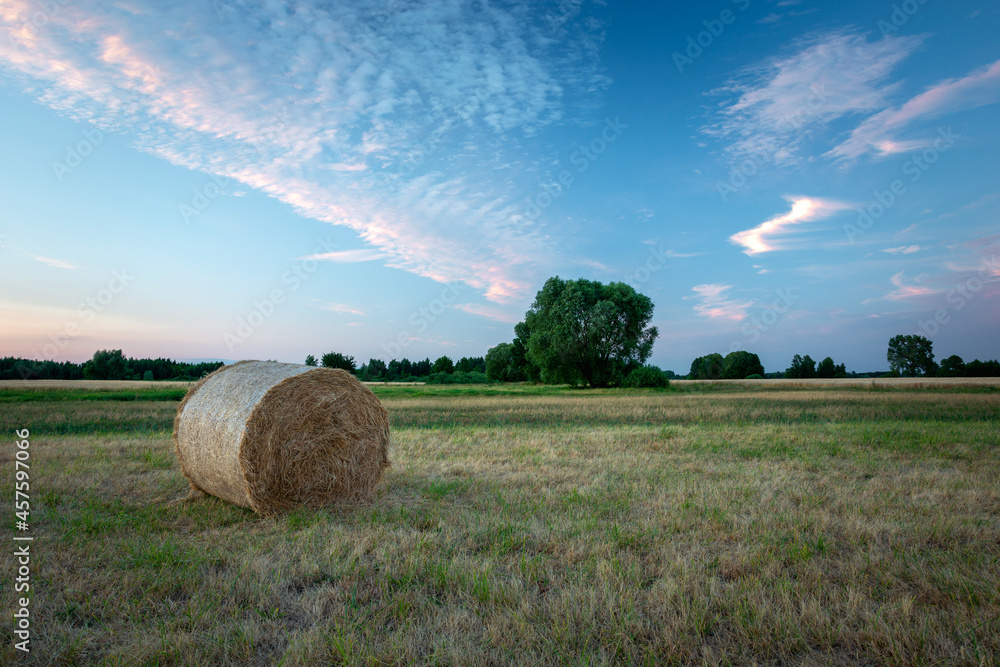 A single bale of hay on a meadow and the evening sky