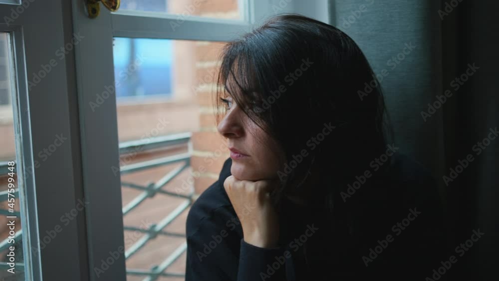 Thoughtful woman looking outside through home window Thoughtful woman looking outside through home window