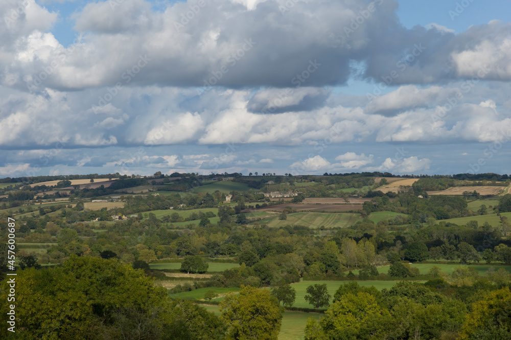 Beautiful landscape in the Cotswolds in the United Kingdom with meadows and fields and blue sky with many clouds