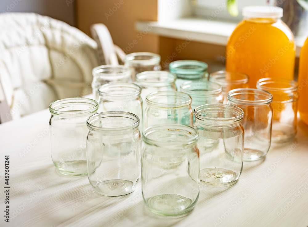 Composition of a large number of jars and three jars of honey standing on a white table against a background of light Composition of a large number of jars and three jars of honey standing on a white table against a background of light