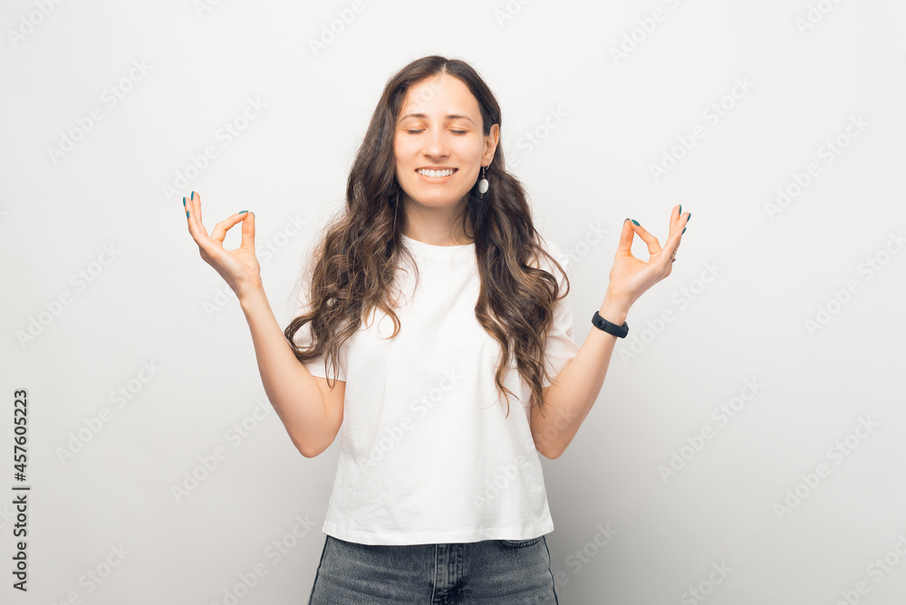 Beautiful young smiling woman is keeping zen state posing in a white studio. Beautiful young smiling woman is keeping zen state posing in a white studio.