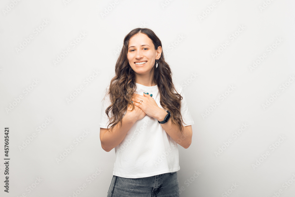 Young woman is showing compassion. Gesturing with hands over chest over white background. Young woman is showing compassion. Gesturing with hands over chest over white background.
