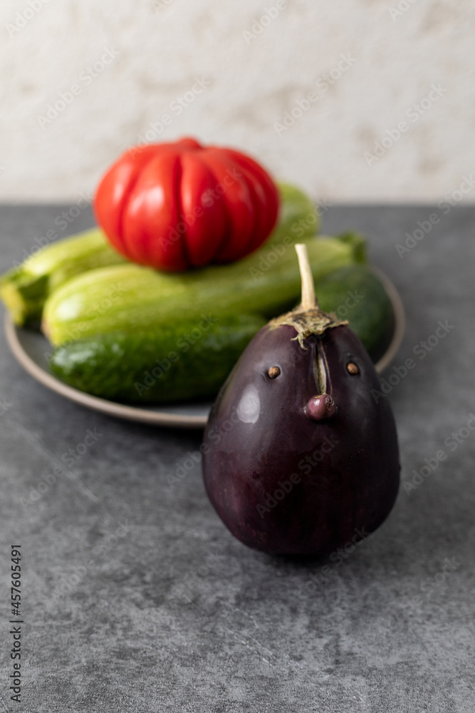 Obraz premium Eggplant with face in a grey background. Funny vegetable. World Vegetarian Day.