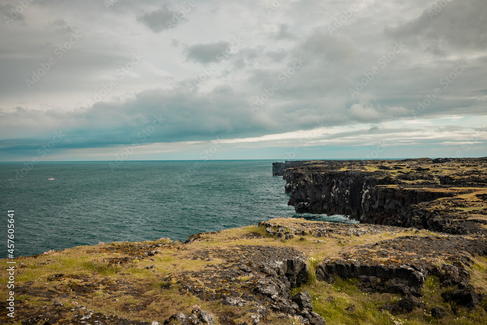 Beautiful landscape view of coast on Iceland around Sfortuloft lighthouse with visible rocks, ledges, natural arch and so on on a cloudy day.