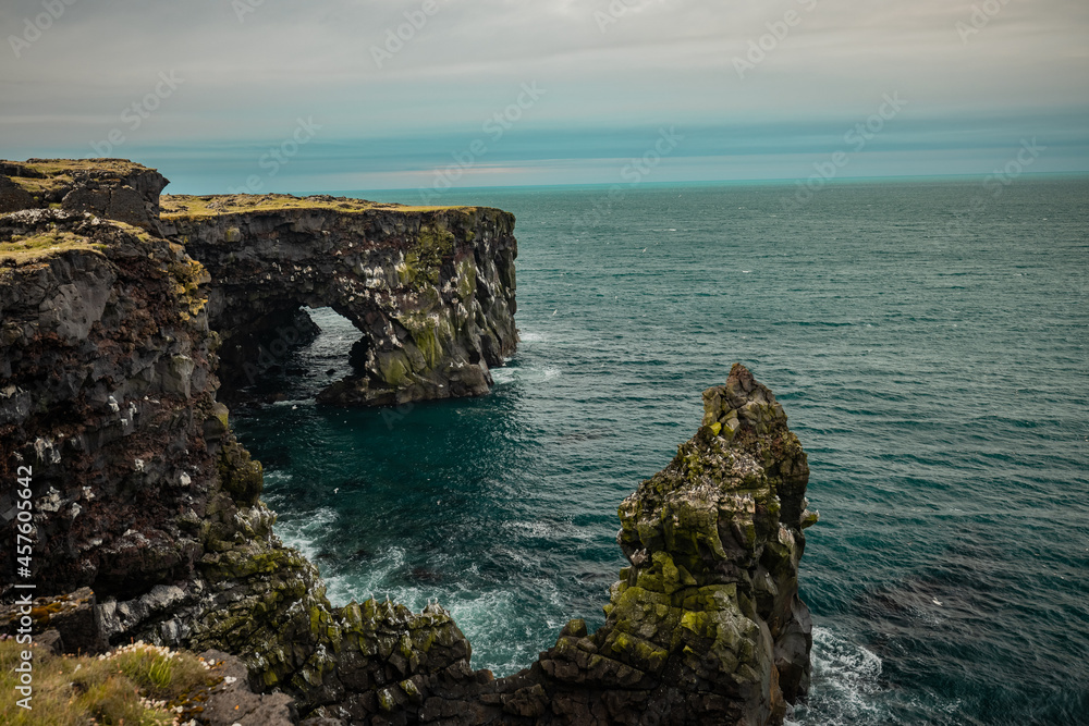 Beautiful landscape view of coast on Iceland around Sfortuloft lighthouse with visible rocks, ledges, natural arch and so on on a cloudy day. Beautiful landscape view of coast on Iceland around Sfortuloft lighthouse with visible rocks, ledges, natural arch and so on on a cloudy day.