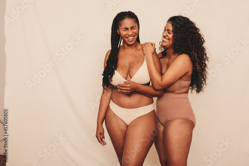 Women laughing together while wearing underwear in a studio