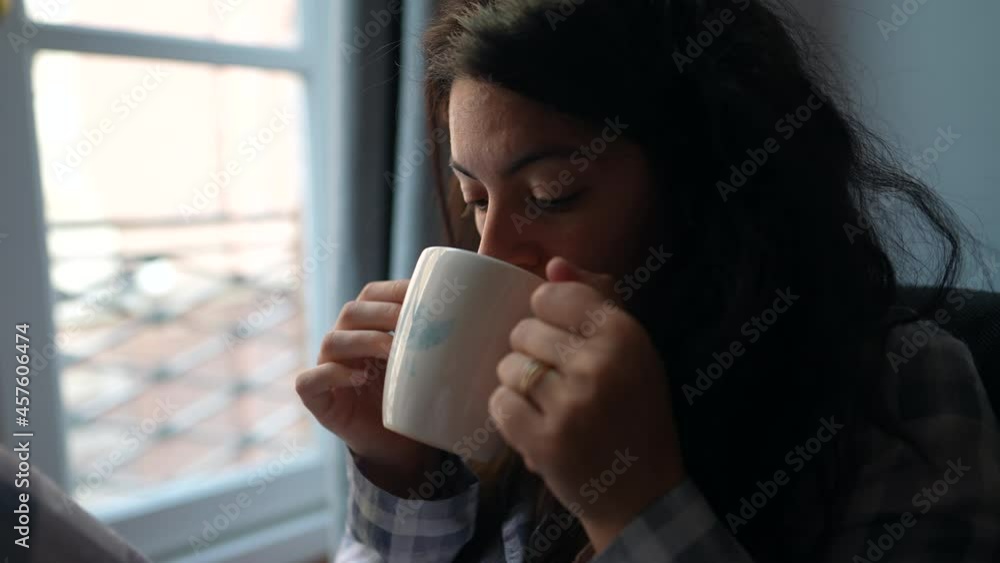 Woman drinking tea of coffee in the morning sitting next to window in the morning Woman drinking tea of coffee in the morning sitting next to window in the morning