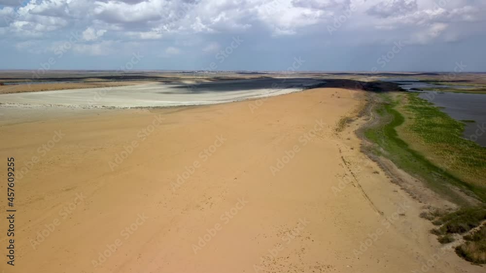 The drone's flight from the semi-desert to the green shore of a drying lake, on the shore of which cows graze. A view to the horizon of a dried-up lake covered with a crust of salt The drone's flight from the semi-desert to the green shore of a drying lake, on the shore of which cows graze. A view to the horizon of a dried-up lake covered with a crust of salt