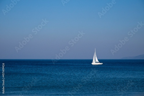 White sail boat on blue ocean.