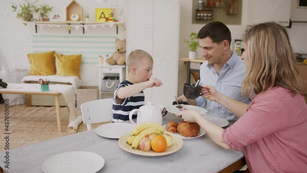 Happy family with down syndrome son at the table, having breakfast. Happy family with down syndrome son at the table, having breakfast.