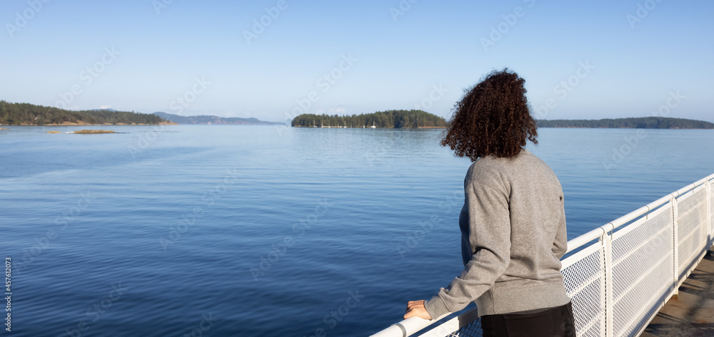 White Caucasian Adult Woman watching the Canadian Nature Scenery from a ferry boat. West Coast of Pacific Ocean. Vancouver Island, British Columbia, Canada.