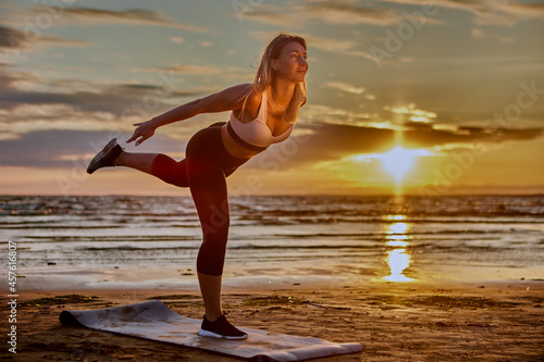 Fototapeta Naklejka Na Ścianę i Meble -  Woman is training yoga on seaside during sunset.