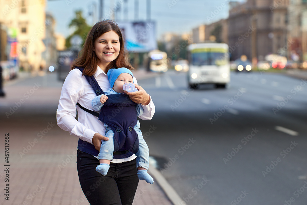 Woman feeds child in sling near traffic during walking. Woman feeds child in sling near traffic during walking.