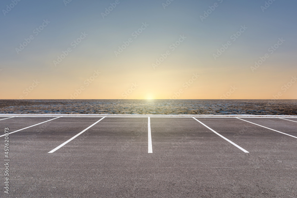 Fototapeta premium Empty parking lot against arid area and beautiful sunset sky.