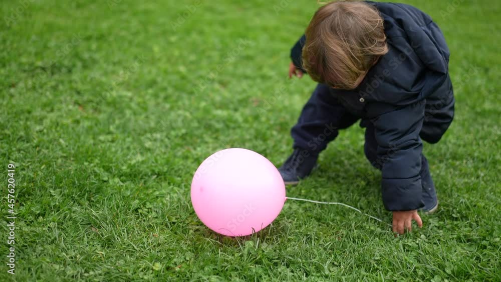 Little boy grabbing balloon and running outside at park. Happy child plays with balloon Little boy grabbing balloon and running outside at park. Happy child plays with balloon