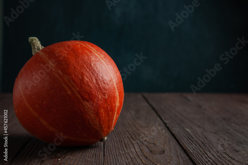 Pumpkin on wooden table in dark mood with copy space.